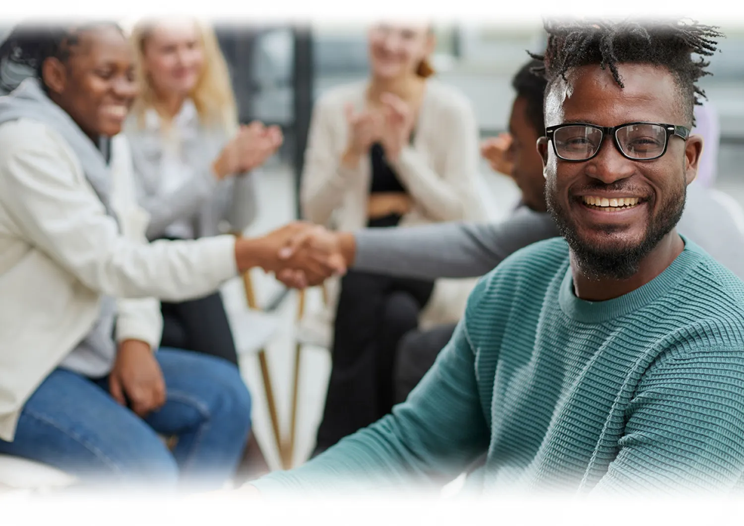 Image of man smiling with several people  meeting in the background 
